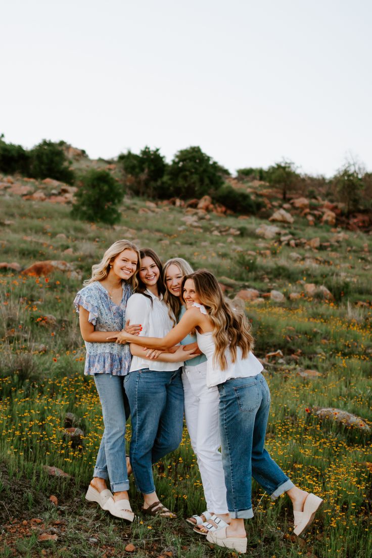 three girls standing together in the grass with their arms around each other