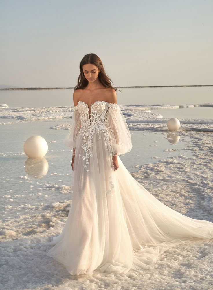 a woman standing in the snow with her arms behind her head wearing a wedding dress