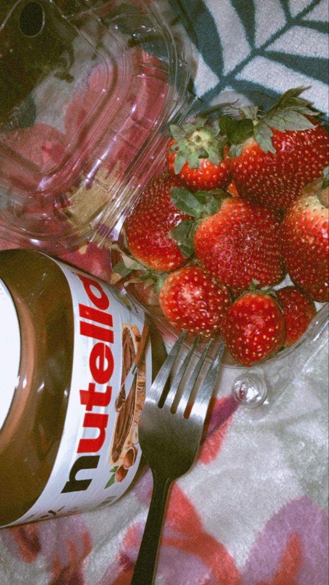 there is a jar of nutella next to strawberries and a fork on the table