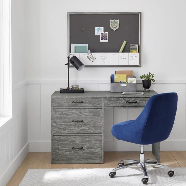 a blue chair sits in front of a desk with a blackboard on it and a white rug