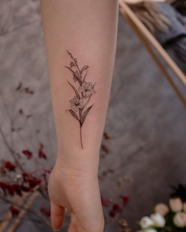 a small flower tattoo on the left inner arm and wrist is shown in black ink