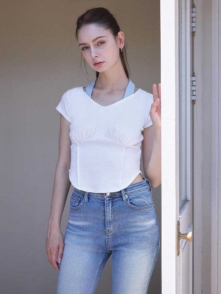 a woman standing in front of an open door with her hand up to the side