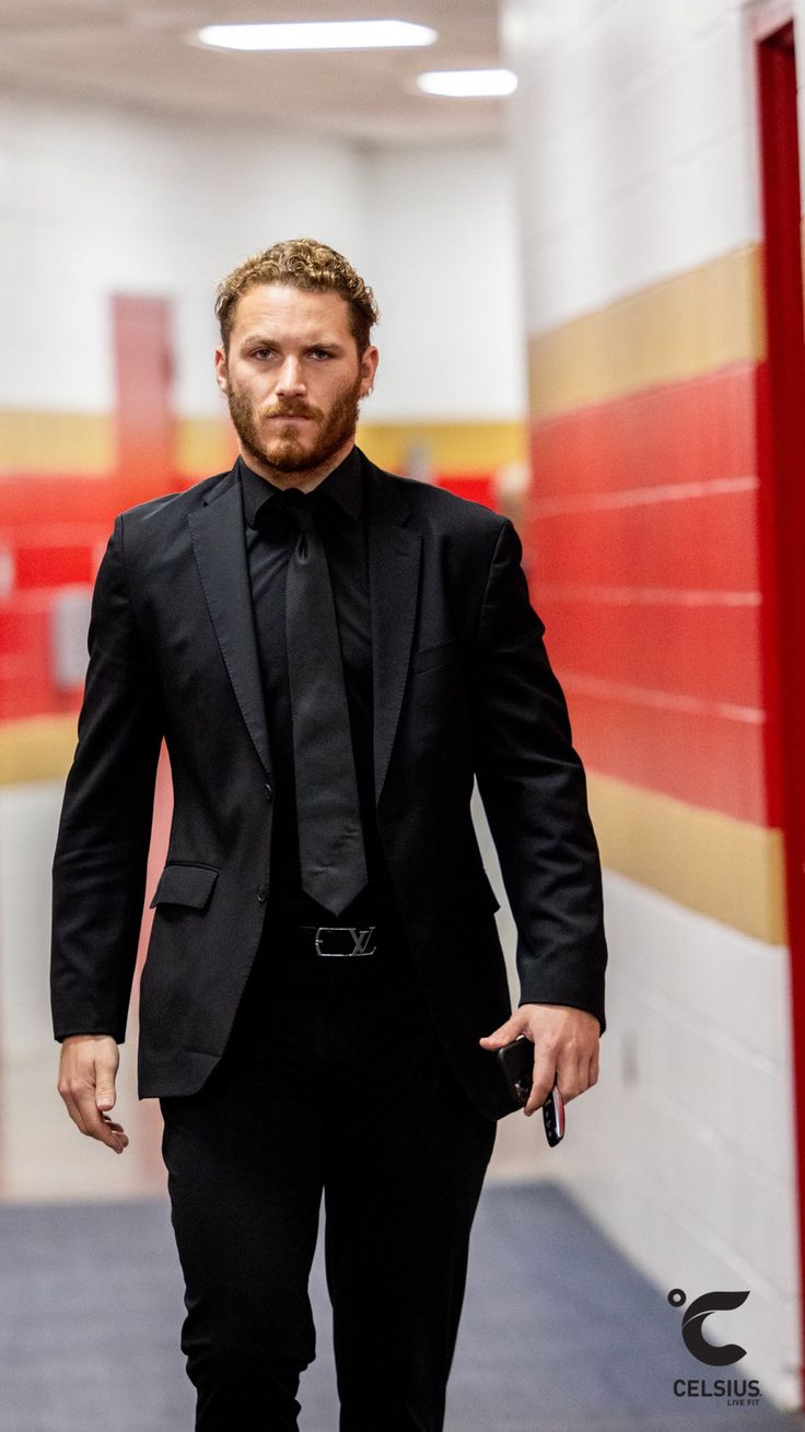 a man in a suit and tie walking down a hallway with his hand in his pocket