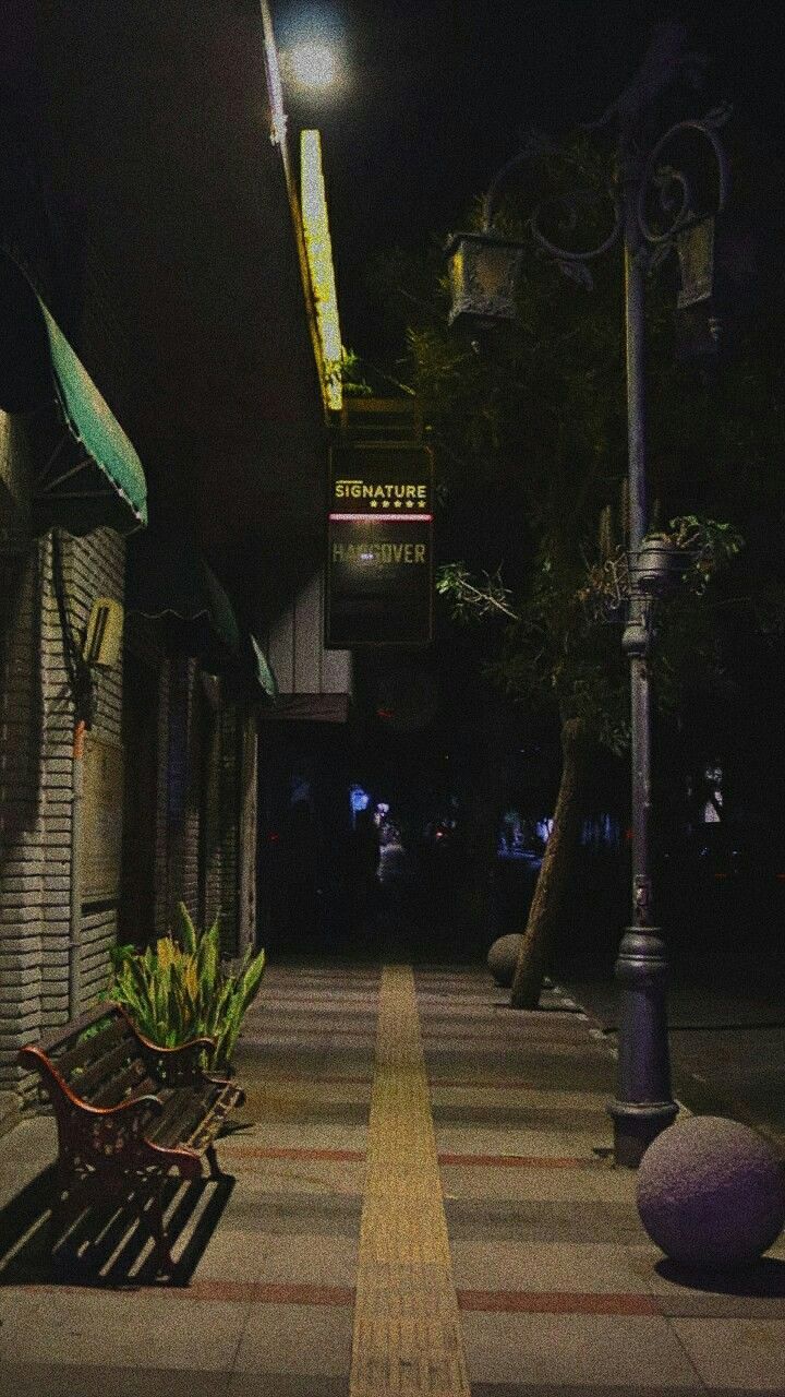 a bench sitting on the side of a road next to a street light