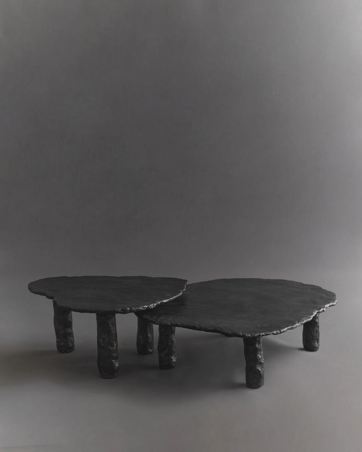 two tables made out of concrete with one sitting on the other side and another standing up