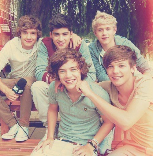 a group of young men sitting next to each other on top of a wooden bench