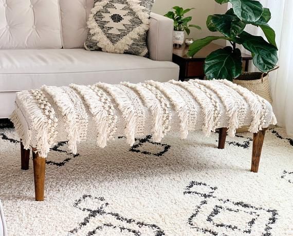 a white couch sitting next to a wooden bench on top of a carpeted floor