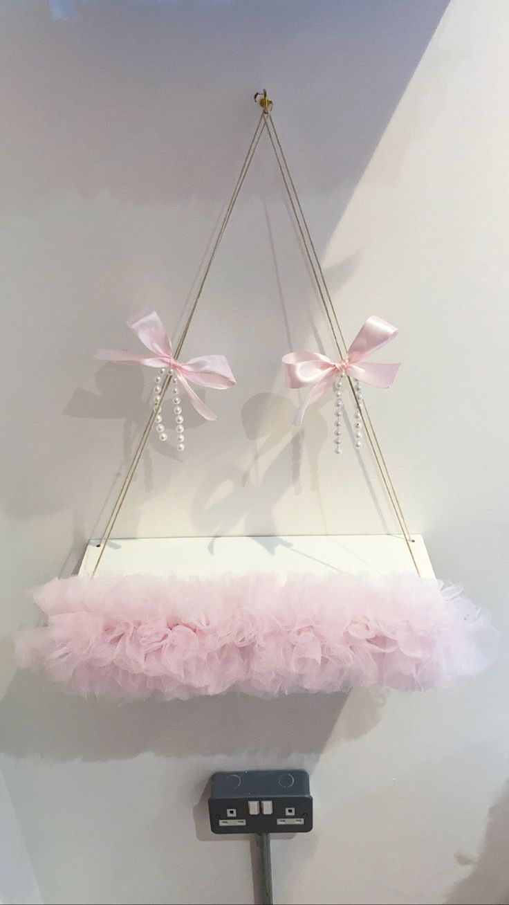 a pink and white display with two bows hanging from it's sides on a metal pole