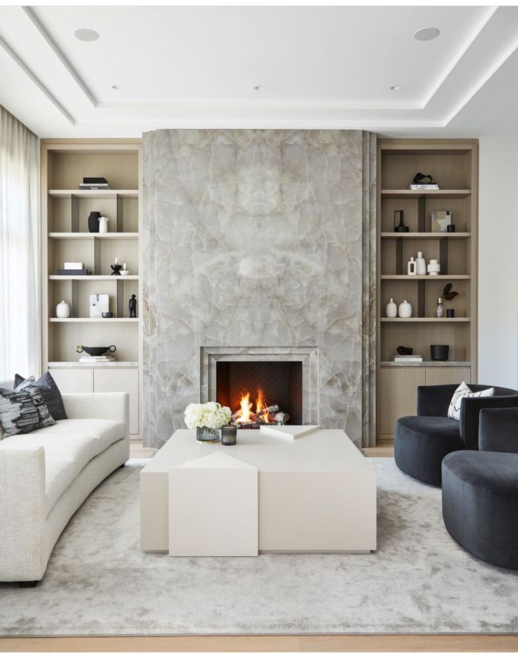 a living room with white furniture and a fire place in the middle of the room