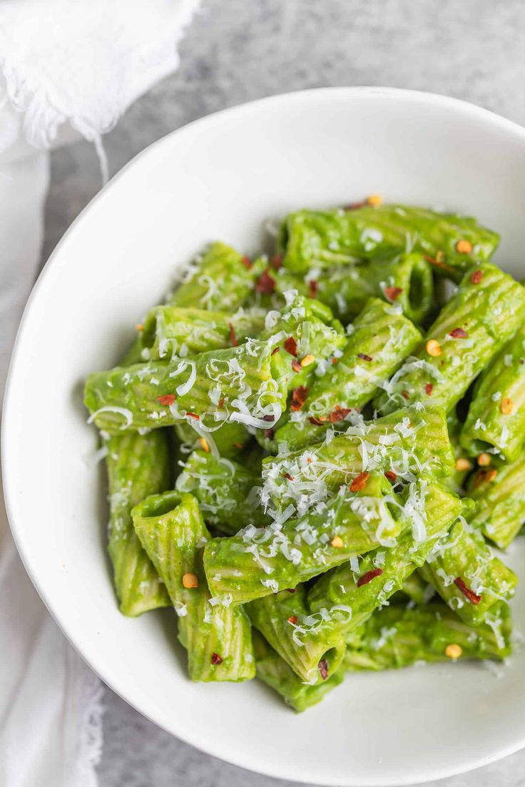 a white bowl filled with green vegetables covered in parmesan sprinkles