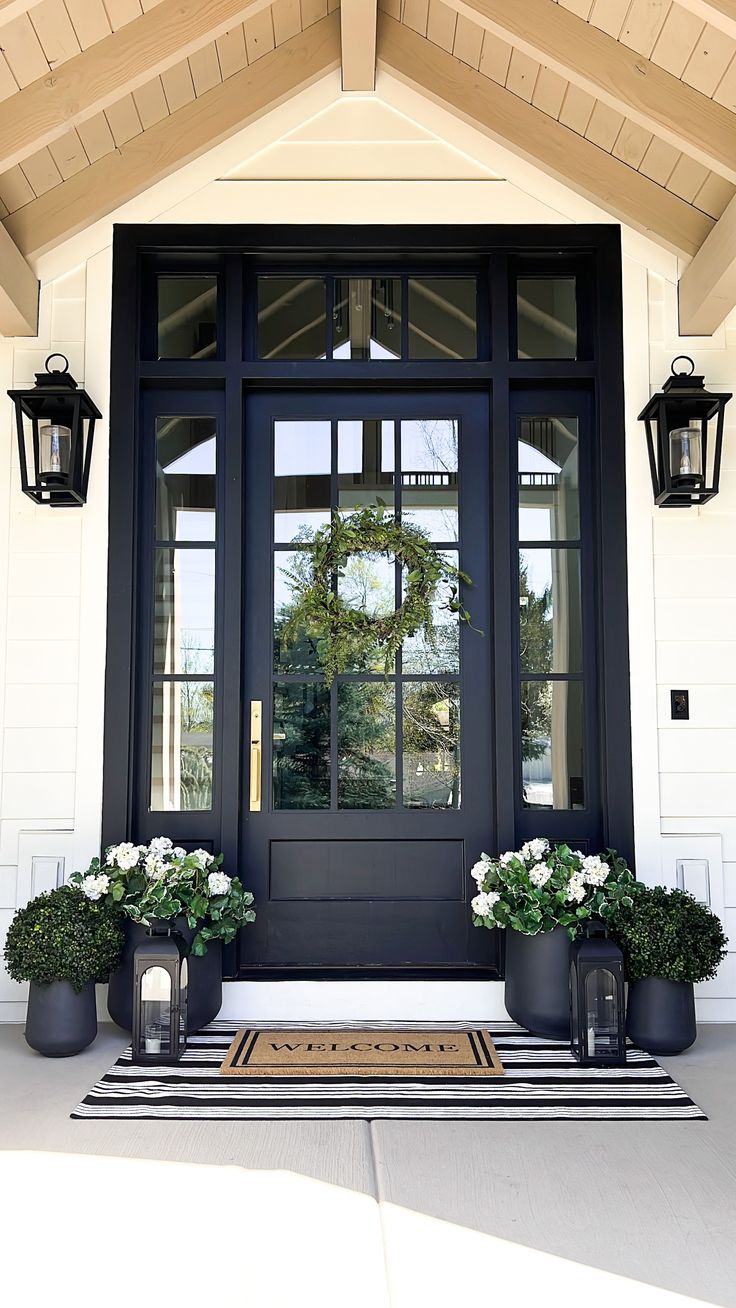 a black front door with two potted plants