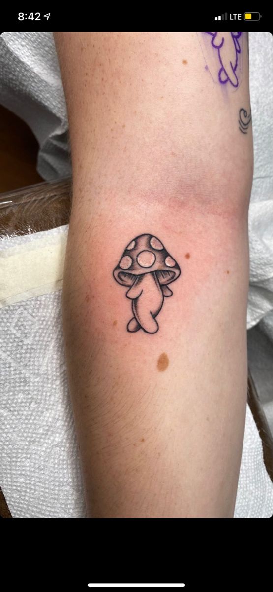 a small mushroom tattoo on the arm