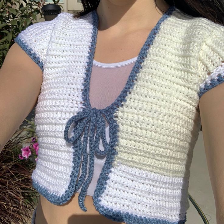 a close up of a woman wearing a white and blue crochet top with an attached tie