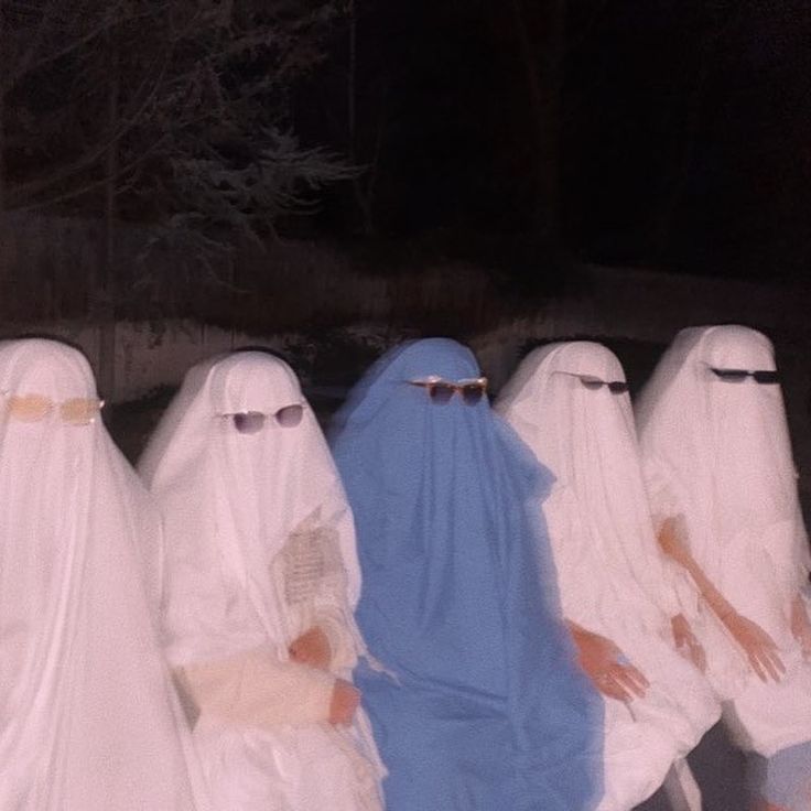 several people dressed in white and blue are standing outside at night with their hands on their hips