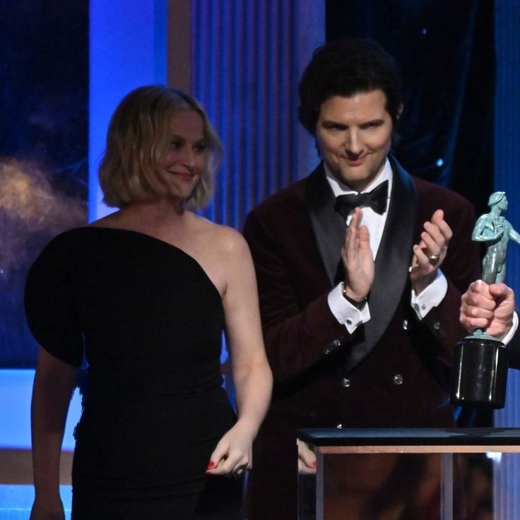 two women and a man standing next to each other at an awards event with one holding up the award for best performance in a musical series