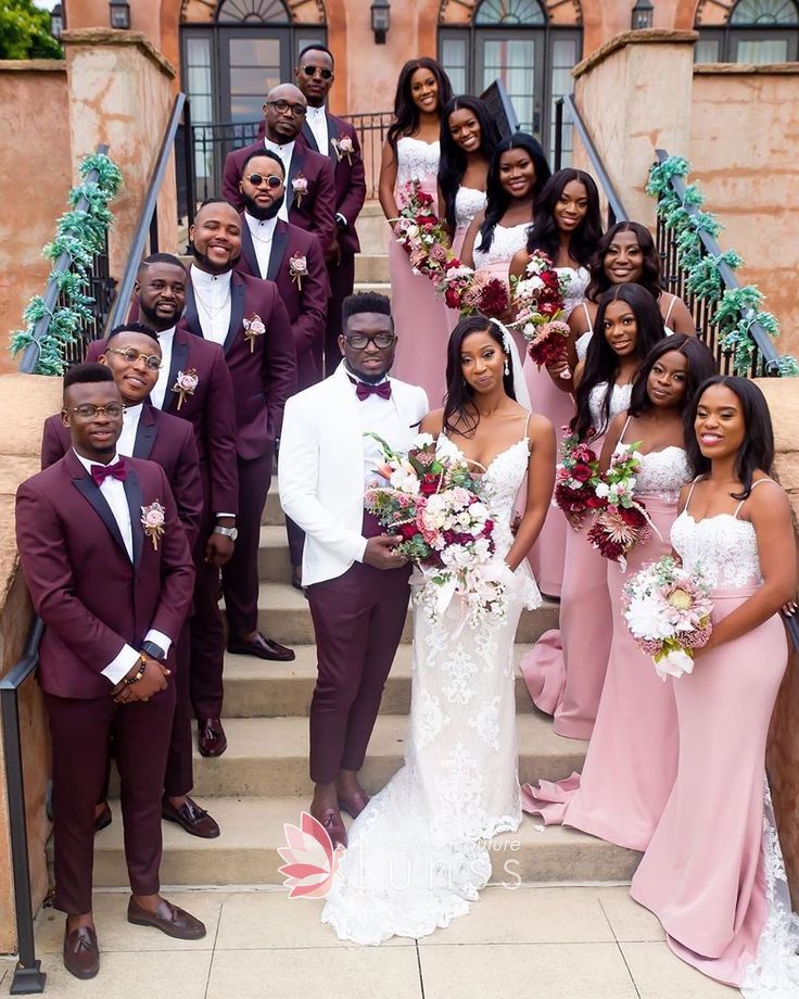 a group of people in formal wear posing for a photo on some steps with flowers