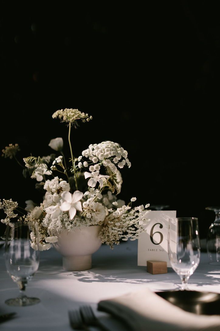 the table is set with white flowers and wine glasses