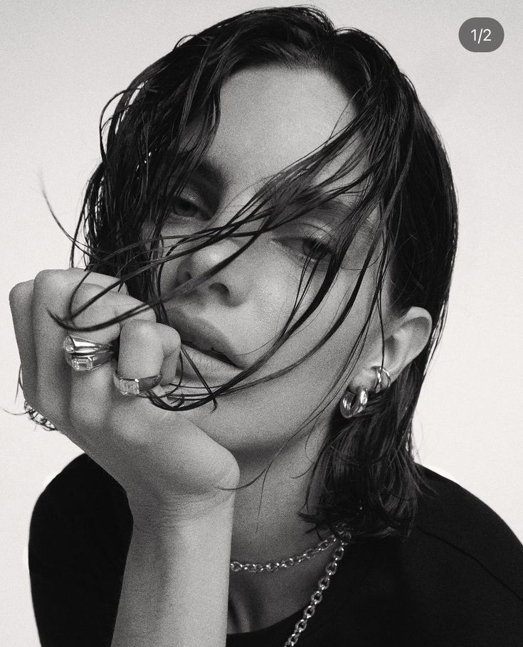 a black and white photo of a woman with her hair blowing in the wind,