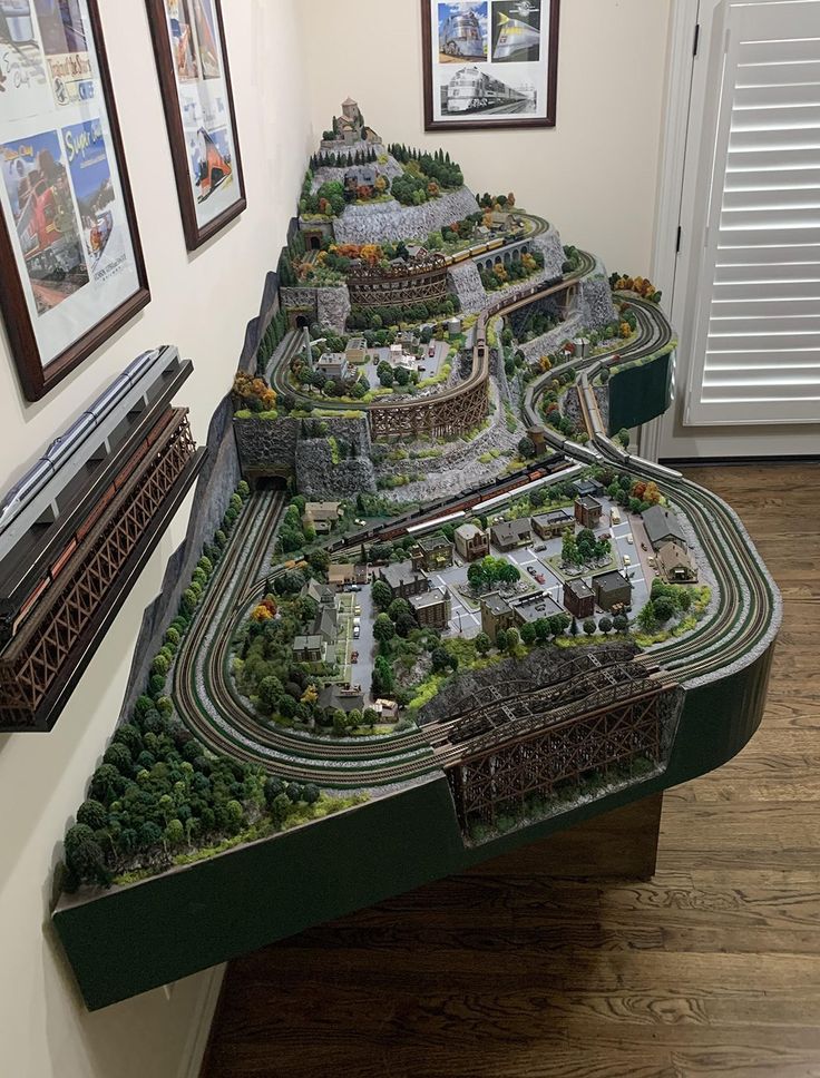 a model train set sitting on top of a wooden table next to pictures and frames