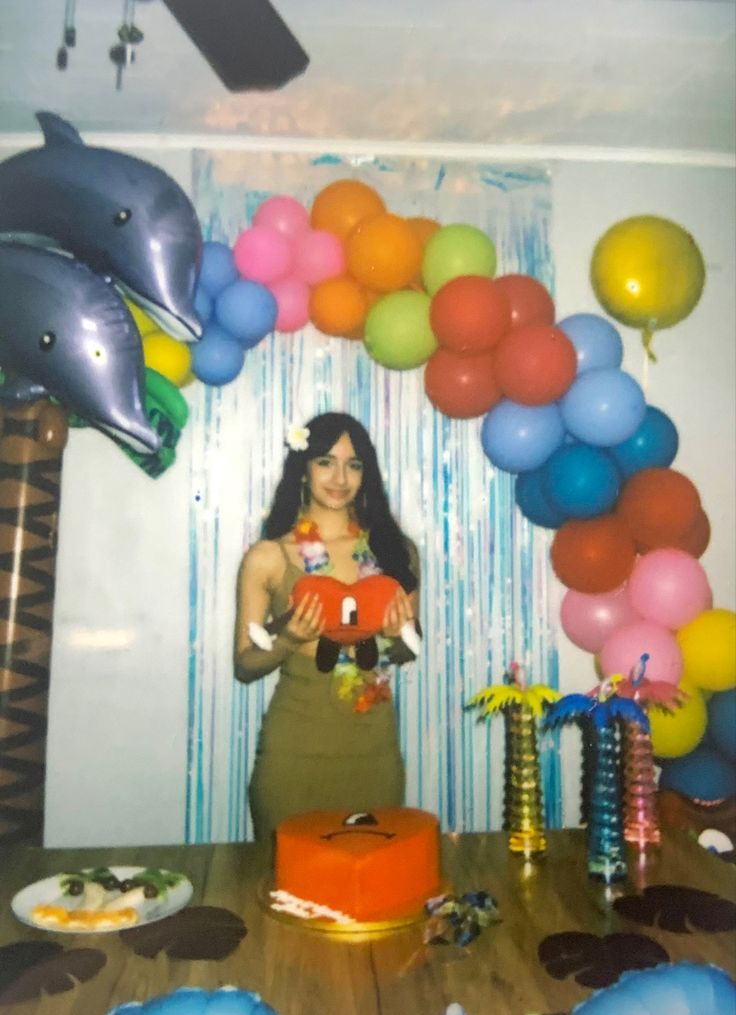 a woman standing in front of a table with balloons and other items on the table