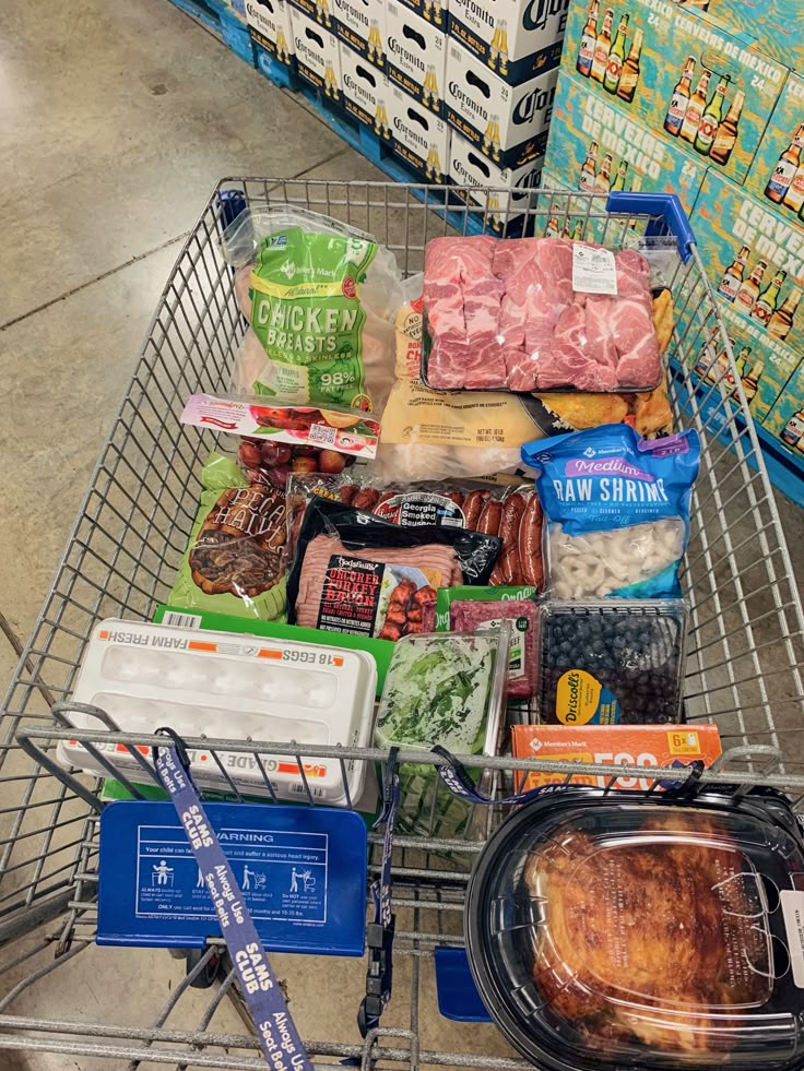 a shopping cart filled with meat and other food items next to some boxes of milk