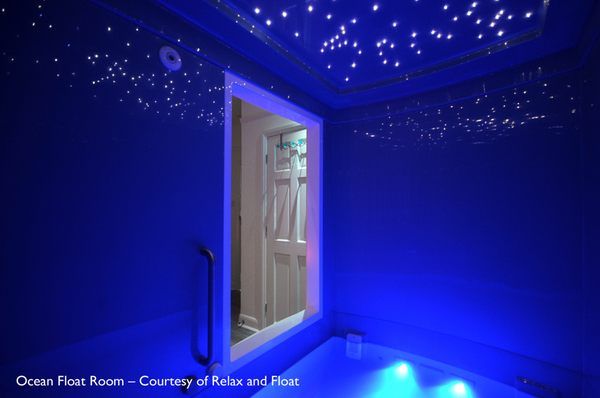 a bath room with a mirror and lights on the wall next to an open door