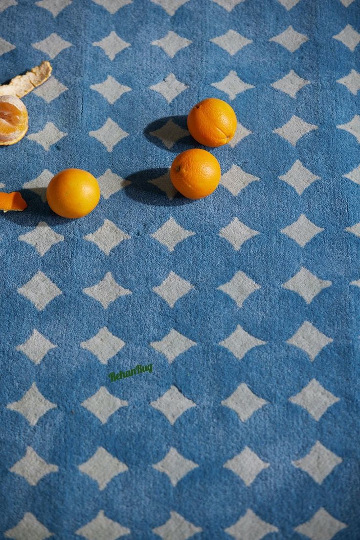 three oranges are on a blue and white checkered tablecloth