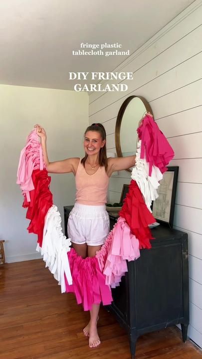 a woman standing in front of a mirror holding up her pink and white ruffled skirt