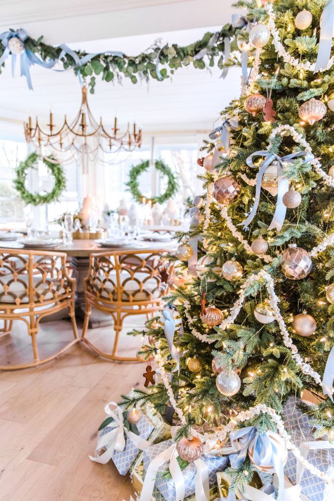 a decorated christmas tree in the middle of a dining room with blue and gold decorations