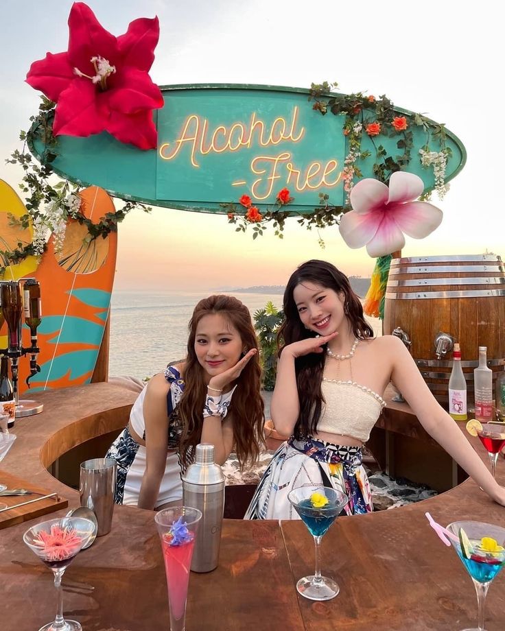 two young women sitting at a table with drinks in front of the sign that says aloha free