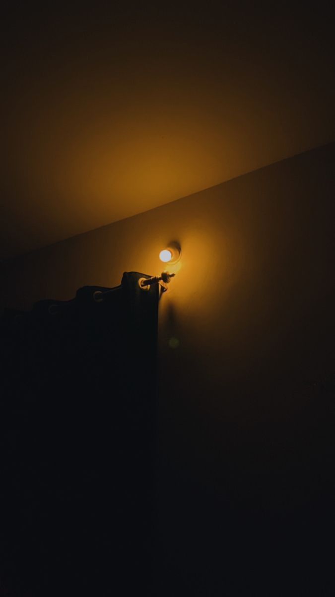 a dark room with a lamp on the wall