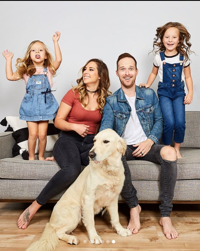 a family sitting on a couch posing for a photo with their dog and two children