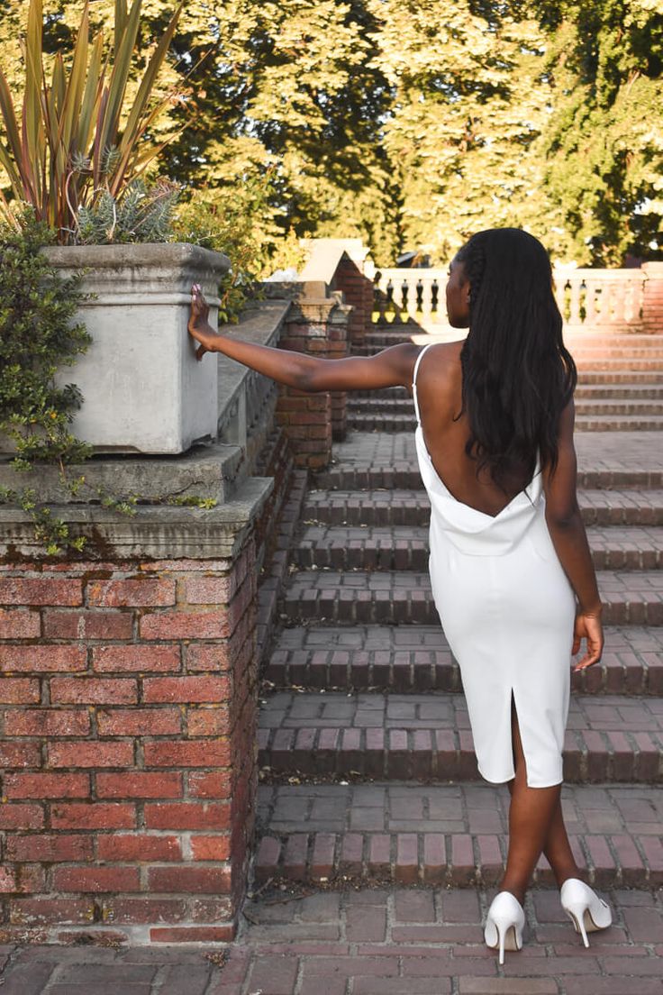 a woman in a white dress standing on some steps with her arms out to the side