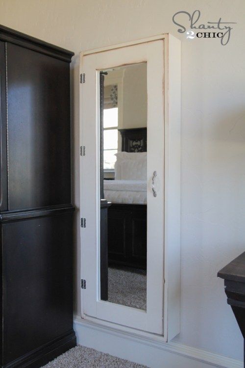 a black armoire and mirror in a room with carpeted flooring on the floor