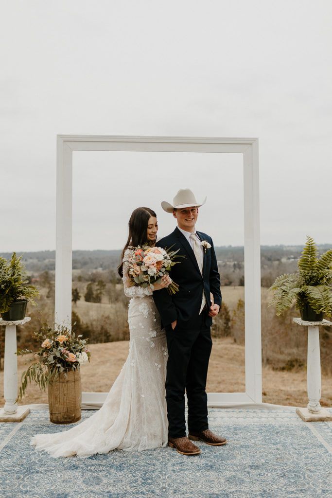 a bride and groom standing next to each other in front of a large white frame