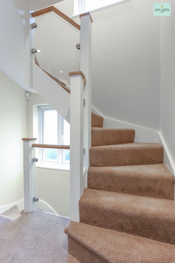 an empty staircase with carpeted steps leading up to a window in the room behind it