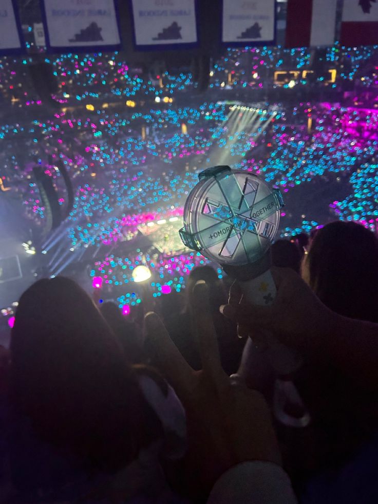 people taking pictures with their cell phones in front of a large crowd at a concert