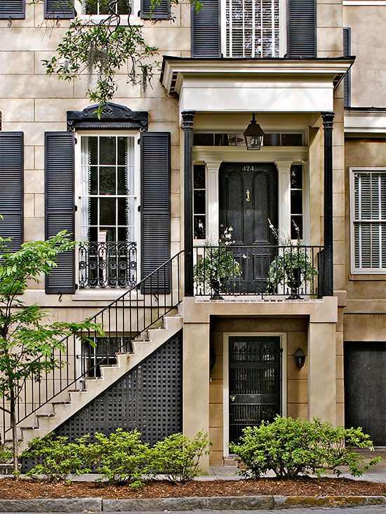 an old building with black shutters and stairs