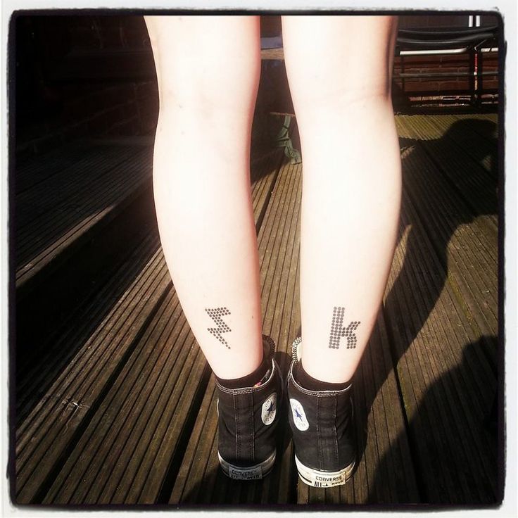 a person with tattoos on their legs standing on a wooden floor next to a bench