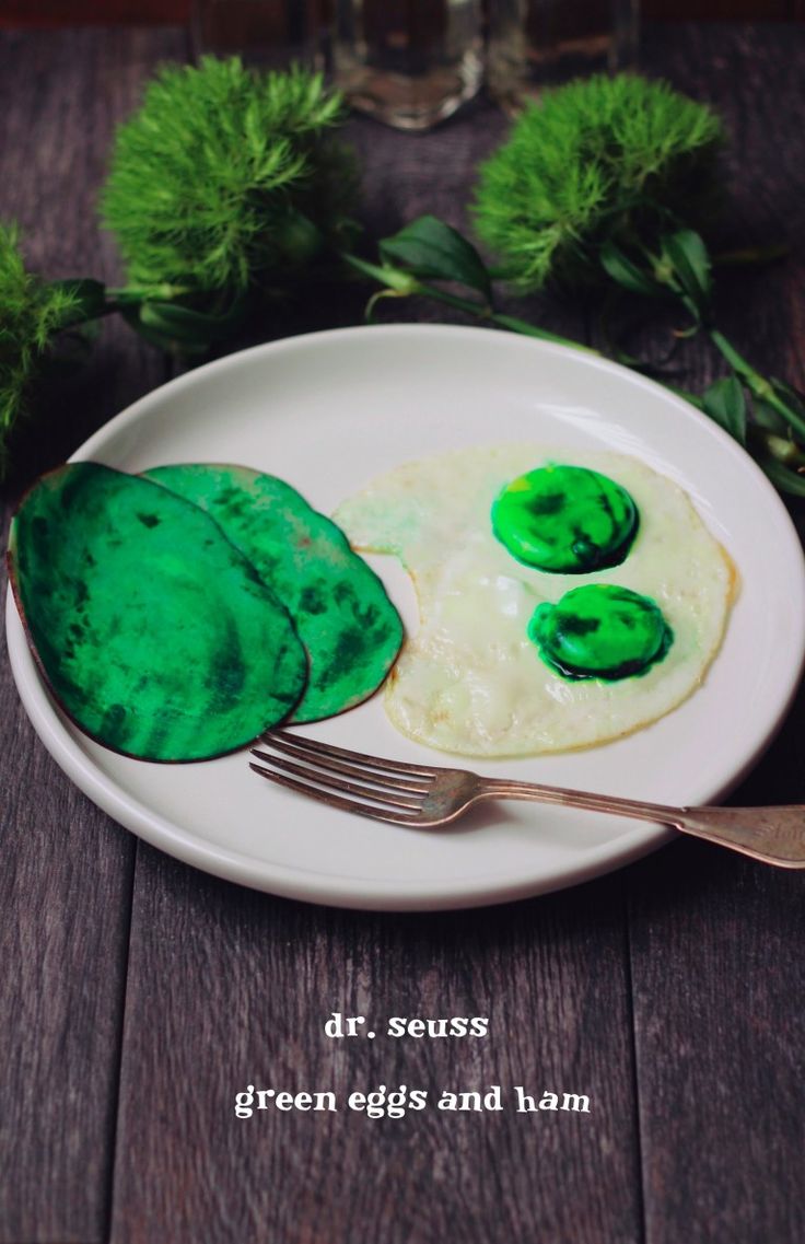 a white plate topped with eggs and green leafy toppings next to a fork