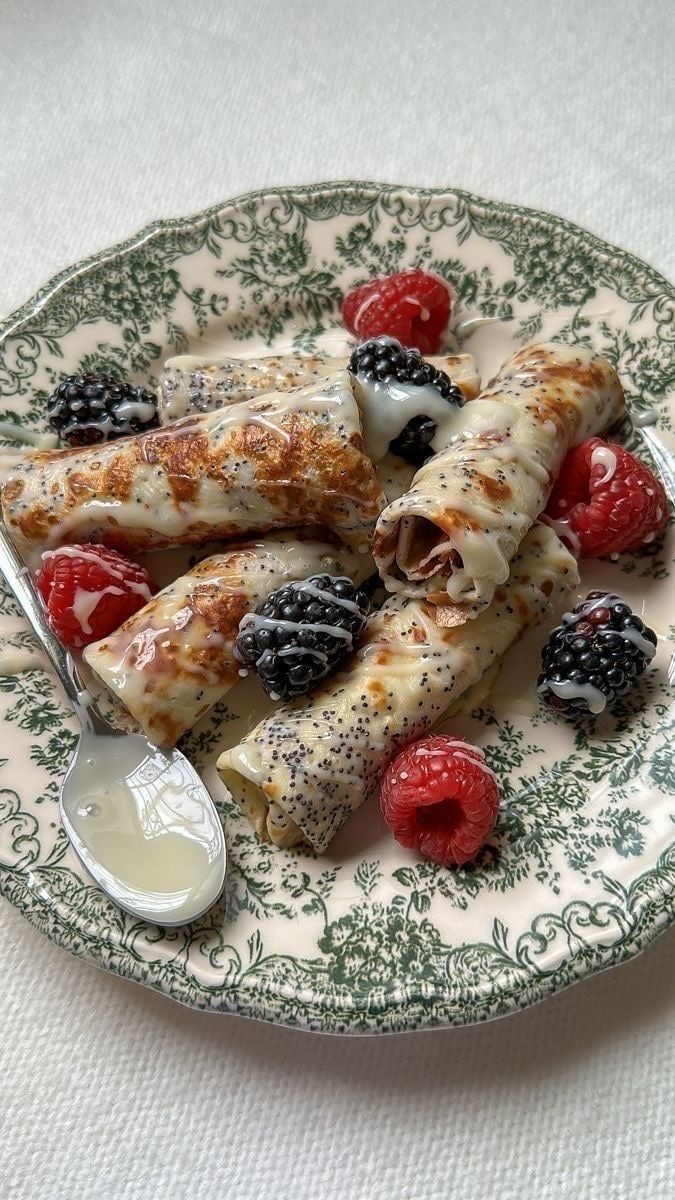 a plate topped with fruit covered pastry next to a bowl of yogurt and raspberries