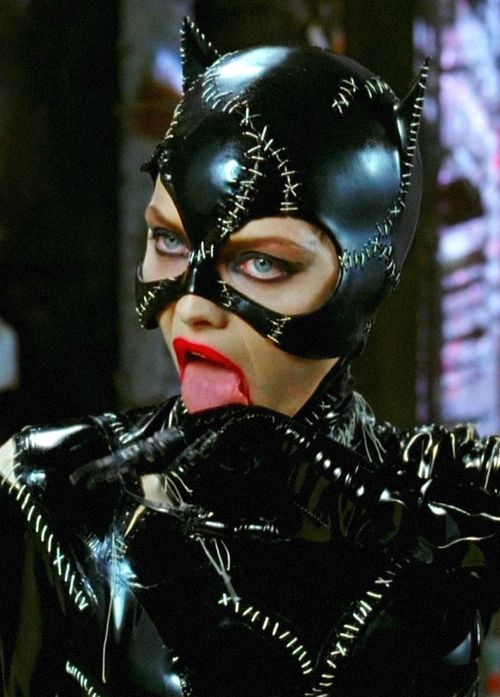 a woman wearing a black cat mask with her tongue out and tongue out in front of her face