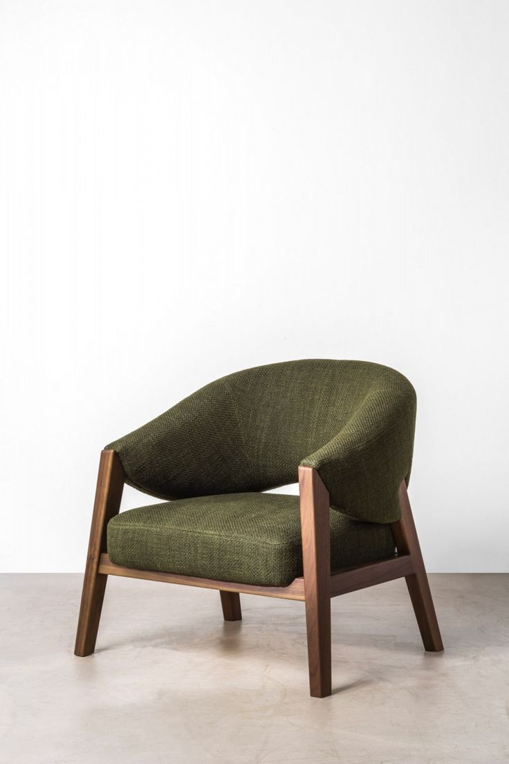 a green chair sitting on top of a cement floor next to a white wall and wooden frame