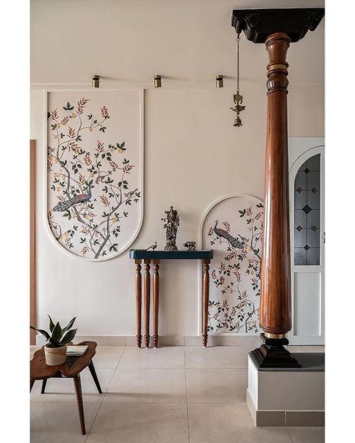 a room with two paintings on the wall and a wooden table in front of it