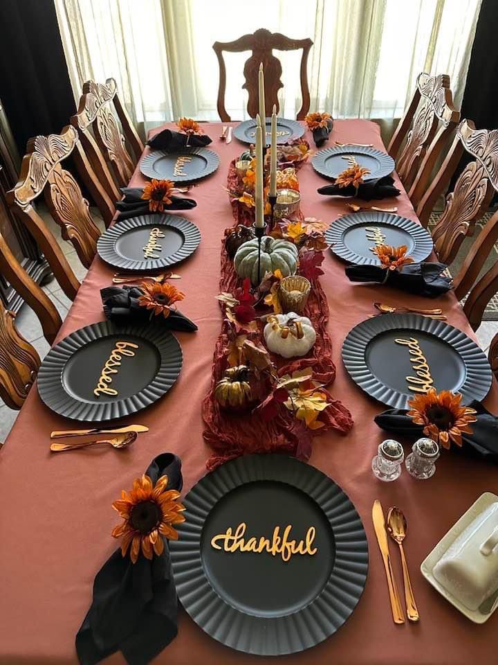 the table is set for thanksgiving dinner with pumpkins and sunflowers