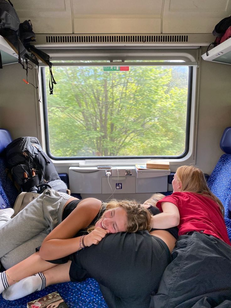 two women are laying on the floor in a train car with their arms around each other