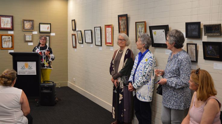 several women are standing in front of a podium with pictures on the wall behind them