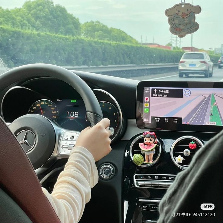 a person driving a car with a gps device in their hand and an image of a cupcake on the dashboard