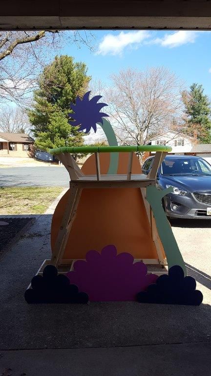 a planter that is sitting on the ground in front of a car parked next to a house