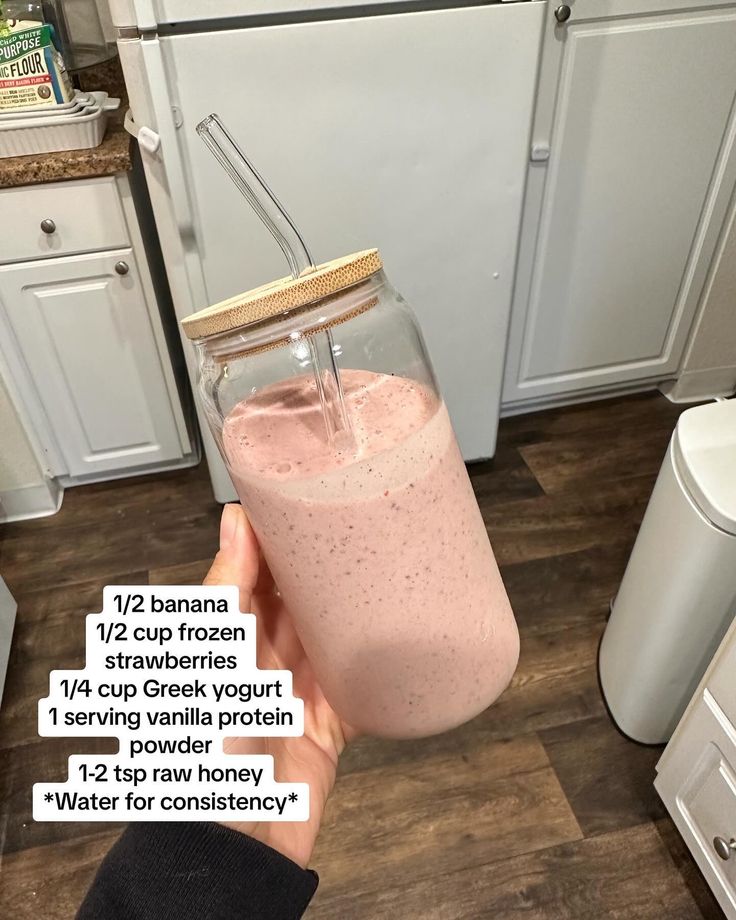 a person is holding a glass jar filled with pink smoothie